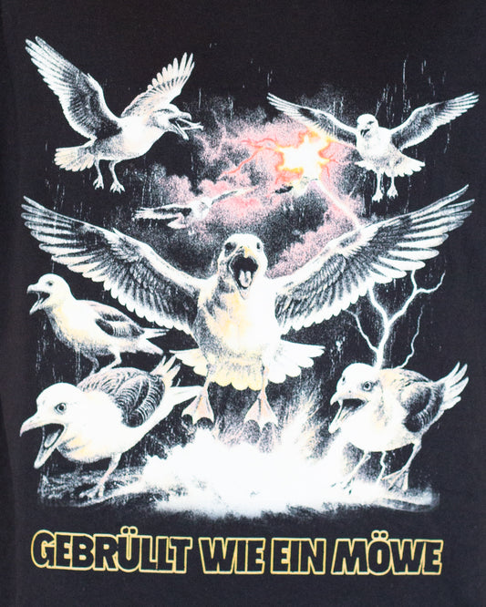 Detailaufnahme des Frontprints: Die zentrale Möwe schreit mit offenem Schnabel, umgeben von fliegenden Möwen und Blitzen, über dem gelben Text „GEBRÜLLT WIE EIN MÖWE“.